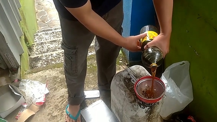 Warga Sedang Menuangkan Minyak Jelantah ke dalam Jerigen di Bank Sampah Puspasari. (Foto:Hasbi-Radartv)